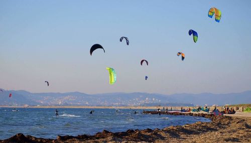 People kiteboarding in sea against clear sky