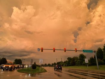 Vehicles on road against sky at sunset