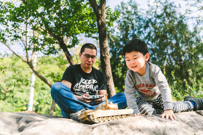 Portrait of young man sitting on tree