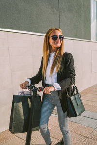 Fashion woman with shopping bags on electric scooter in the street