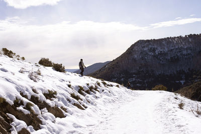 Full length of woman walking on snow covered land against sky