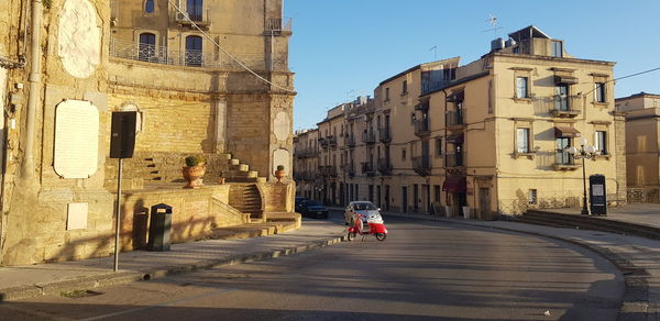 Woman on street amidst buildings in city
