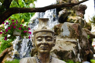 Close-up of statue against trees and waterfall