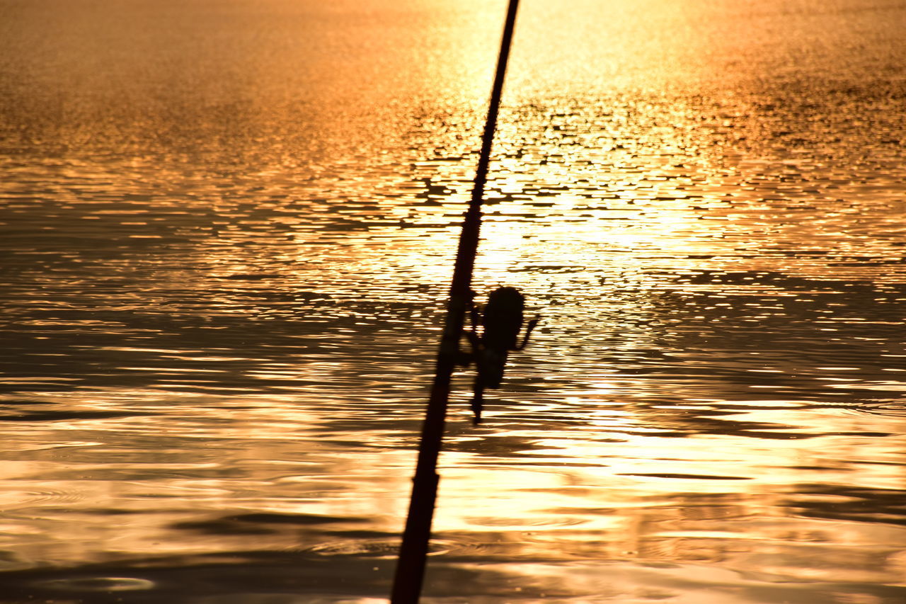 SILHOUETTE PERSON ON SEA DURING SUNSET