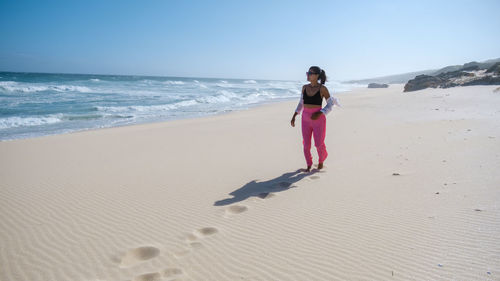 Full length of woman standing at beach against sky