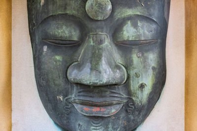 Close-up of buddha statue against wall