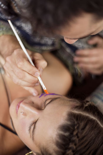Overhead view of makeup artist painting model's face