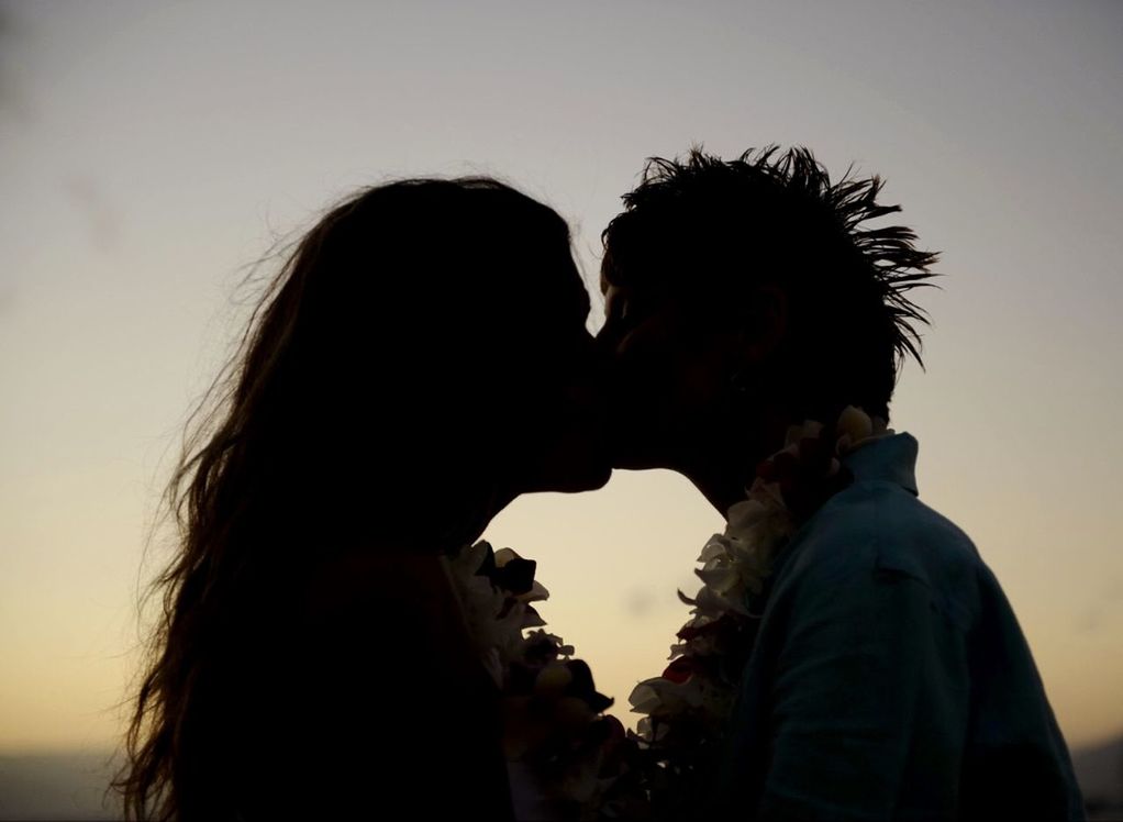 SIDE VIEW OF COUPLE KISSING AGAINST SKY