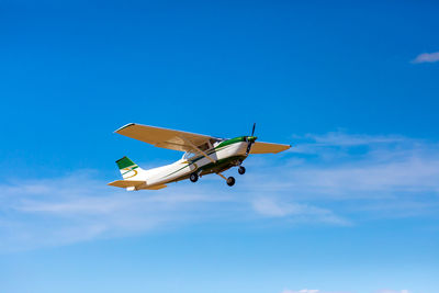 Low angle view of airplane flying against clear blue sky