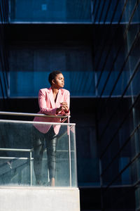 Businesswoman looking away while standing by railing in office