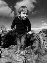 Boy on rock against sky