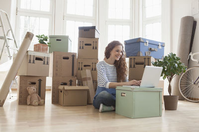 Woman surrounded by cardboard boxes using laptop