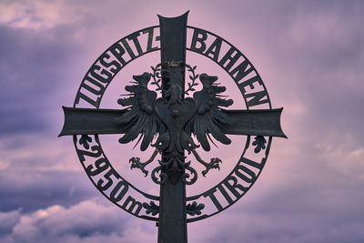 Low angle view of cross sculpture against sky