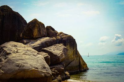 Rock formation on sea shore against sky