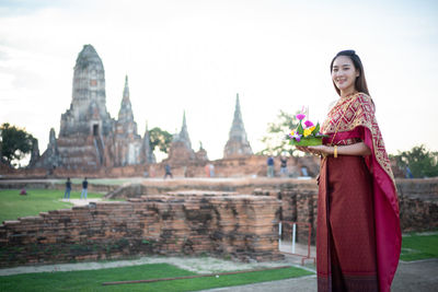 Portrait of woman standing at temple against building