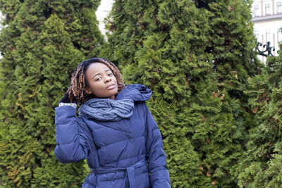 Portrait of woman standing against trees