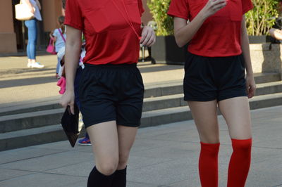 Midsection of female soccer players walking on street