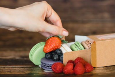 Midsection of person holding strawberries in box