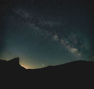 Low angle view of silhouette mountain against sky at night