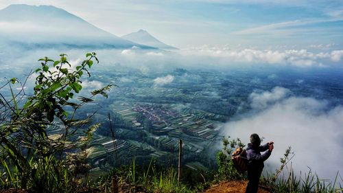 Side view of man on mountain against landscape and sky