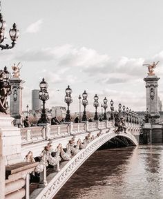 Bridge over river in city against cloudy sky