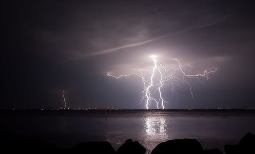 Lightning over sea against sky at night