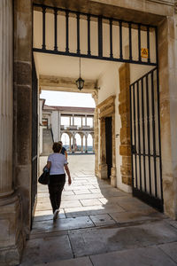 Rear view of woman walking on street amidst buildings