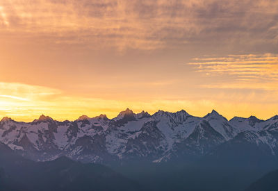 Scenic view of snowcapped mountains against sky at sunset