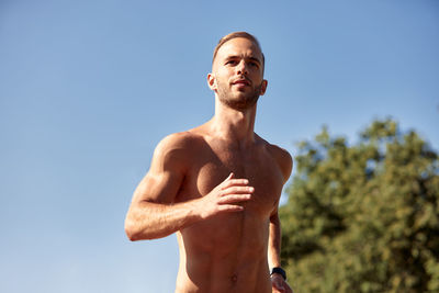 Low angle view of shirtless man standing against sky