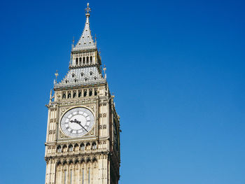 Low angle view of clock tower against clear blue sky