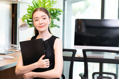 Smiling businesswoman holding laptop at office
