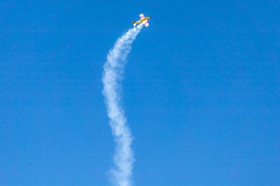 Low angle view of airshow against clear blue sky