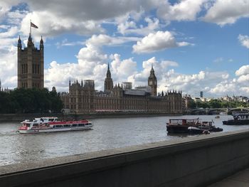 View of buildings by river against cloudy sky