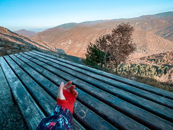 Woman with umbrella on mountain against sky