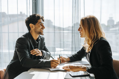 Happy male client talking with female entrepreneur while filling form