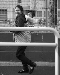 Side view of mother piggybacking daughter while walking on road