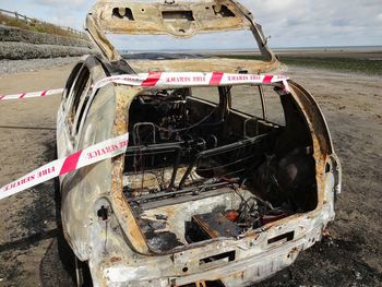 Close-up of abandoned car on field against sky