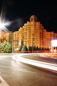 Light trails on city street by buildings at night