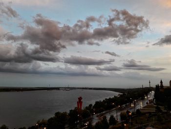 High angle view of illuminated city by sea against sky