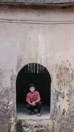 Portrait of man sitting against wall