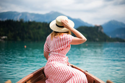 Rear view of woman sitting on boat in lake