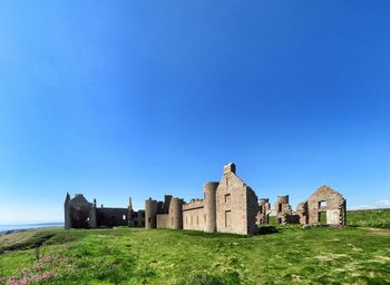 Castle on field against clear blue sky