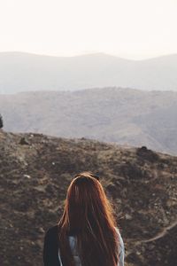 Rear view of woman looking at mountains against sky