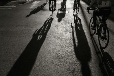Rear view of athletes cycling on street