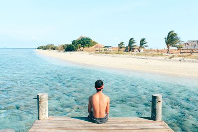 Rear view of man looking at sea against sky