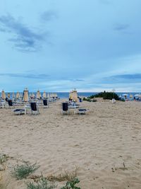 Chairs on beach against sky