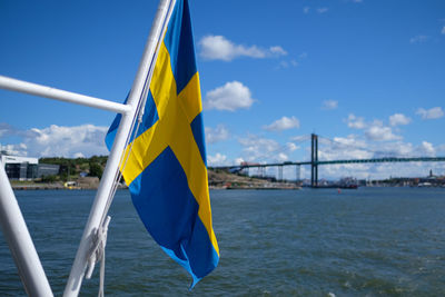Swedish flag in boat moving on river against bridge