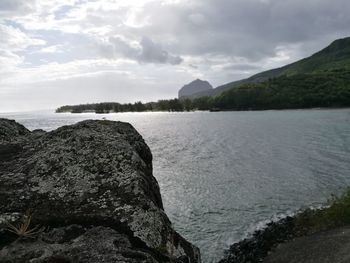 Scenic view of sea by cliff against sky