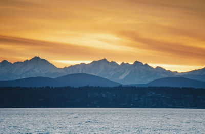 Snow covered olympic mountains over puget sound west of seattle at sunset golden hour.