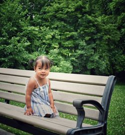 Portrait of cute boy sitting on bench in park